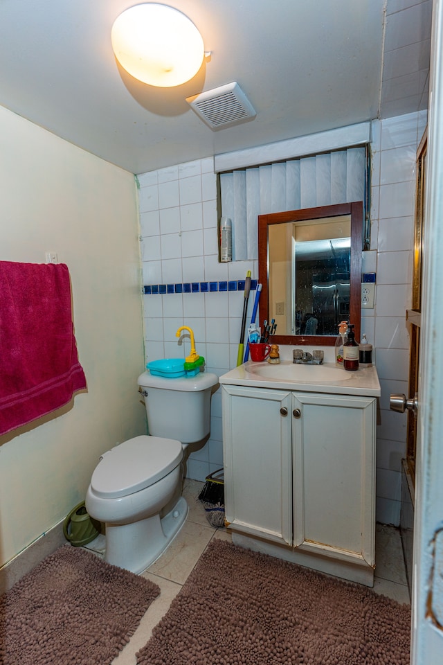 bathroom with visible vents, tile patterned flooring, vanity, toilet, and tile walls