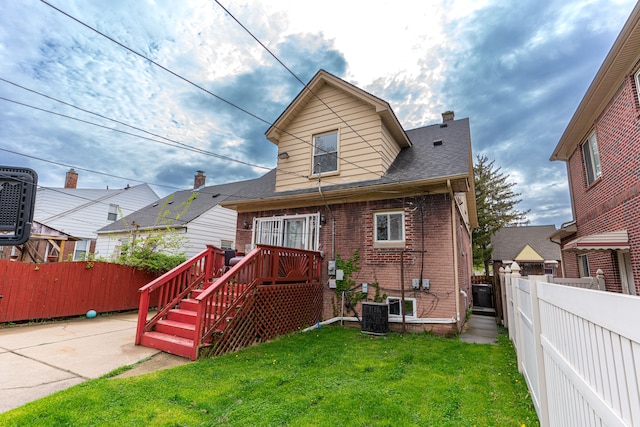 rear view of house with a lawn, a fenced backyard, central air condition unit, and brick siding