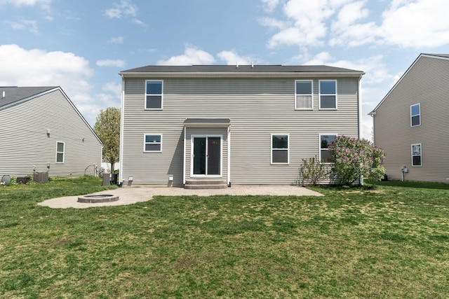 rear view of house featuring central AC, a patio, a fire pit, and a lawn
