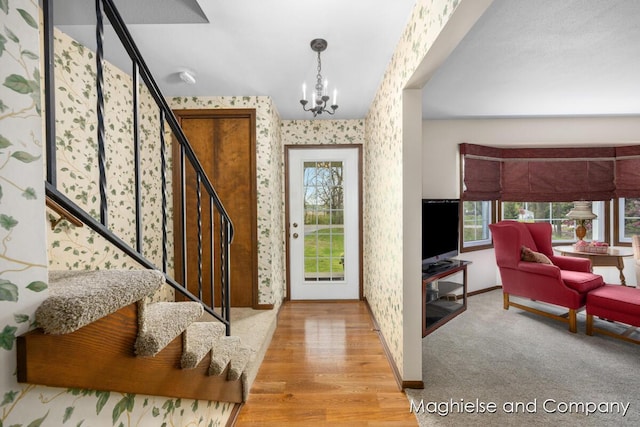entrance foyer with wallpapered walls, stairway, plenty of natural light, a chandelier, and baseboards