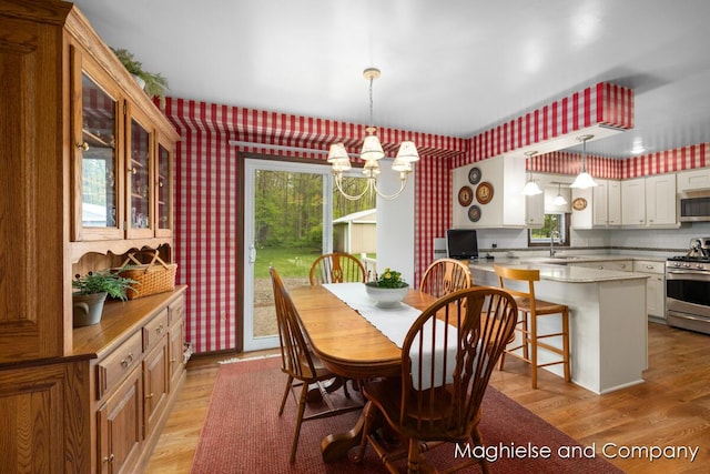 dining space featuring wallpapered walls, light wood finished floors, and a chandelier