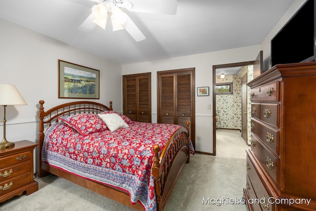 bedroom featuring multiple closets, light carpet, and a ceiling fan