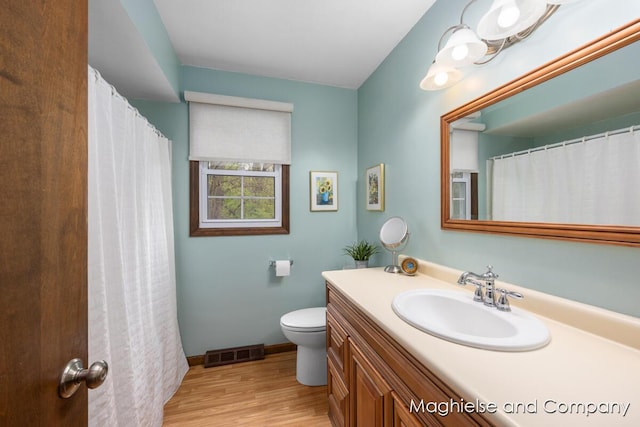 bathroom featuring wood finished floors, toilet, vanity, and baseboards