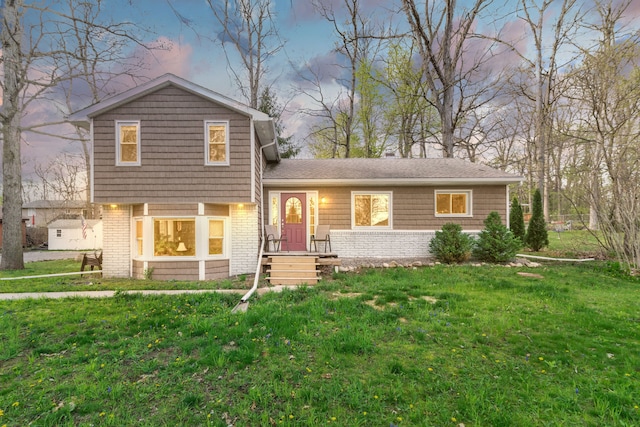 tri-level home featuring a yard and brick siding