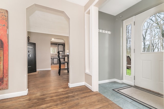 entrance foyer featuring wood finished floors, baseboards, and arched walkways