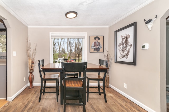 dining area with a wealth of natural light, wood finished floors, baseboards, and arched walkways