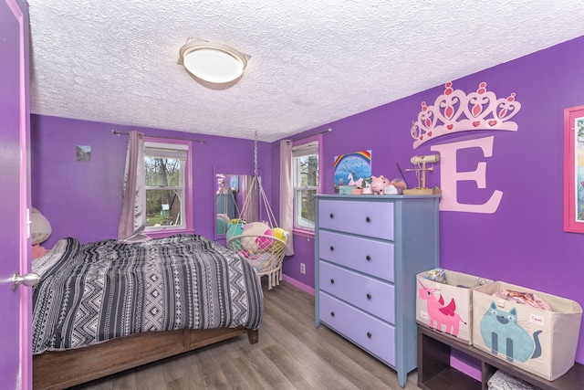 bedroom with a textured ceiling, multiple windows, and wood finished floors