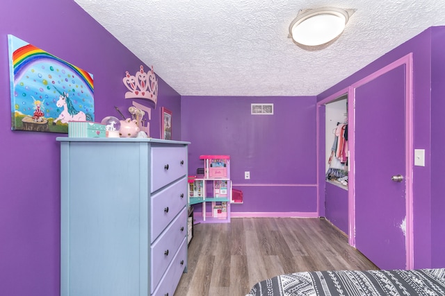 bedroom featuring a textured ceiling, visible vents, and wood finished floors