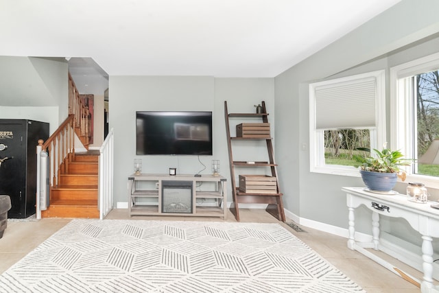 living area featuring light tile patterned floors, stairway, visible vents, and baseboards