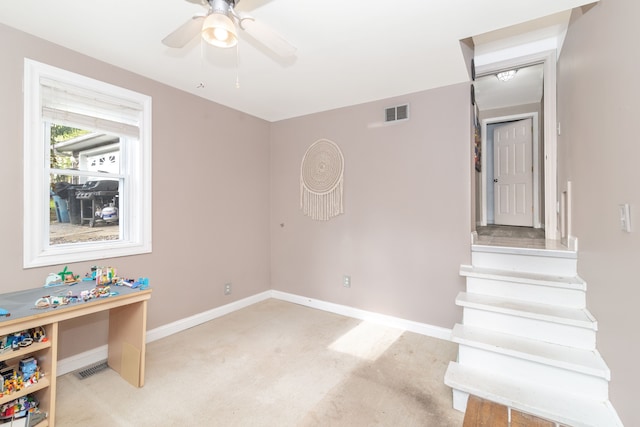 interior space featuring carpet, baseboards, a ceiling fan, and visible vents