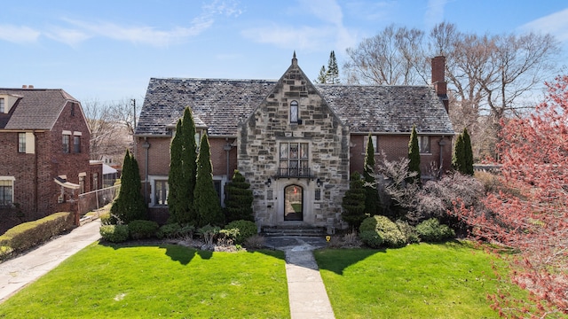 725 W Boston Blvd, Detroit, MI 48202 - tudor-style house with a high end roof, a chimney, a front lawn, and brick siding