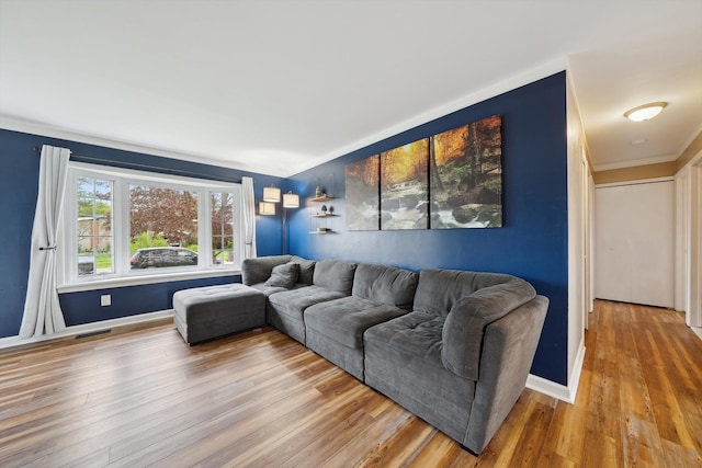 living area with ornamental molding, baseboards, visible vents, and wood finished floors