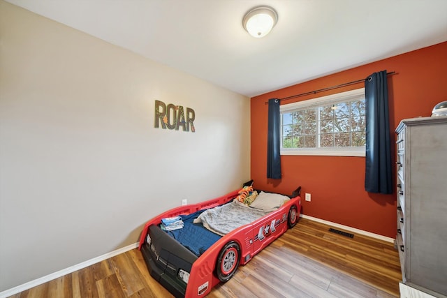 bedroom featuring baseboards, visible vents, and wood finished floors