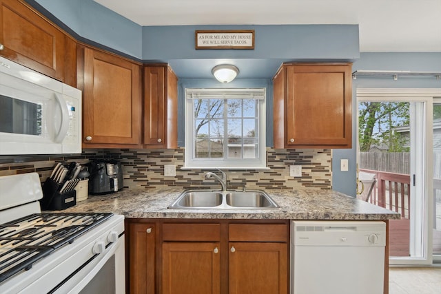 kitchen featuring decorative backsplash, brown cabinetry, a sink, and white appliances