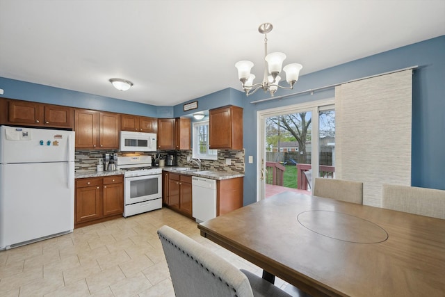 kitchen with a sink, brown cabinetry, a notable chandelier, white appliances, and tasteful backsplash