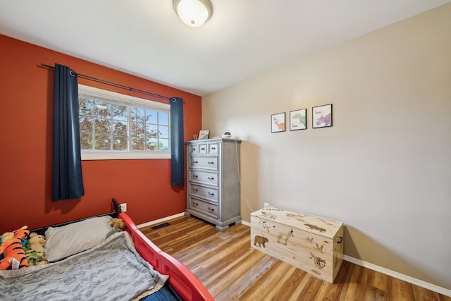 bedroom featuring visible vents, wood finished floors, and baseboards
