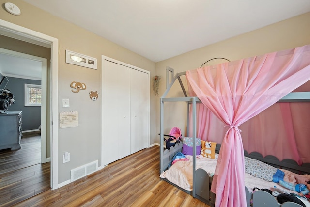 bedroom with baseboards, a closet, visible vents, and wood finished floors