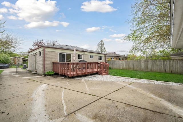 back of property with a lawn, brick siding, a wooden deck, and a fenced backyard