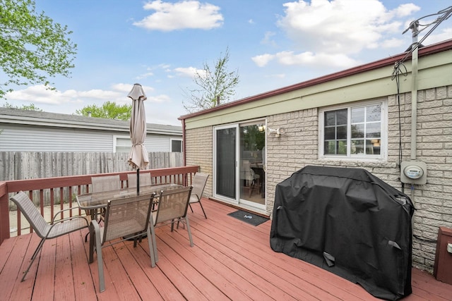 wooden terrace with grilling area, fence, and outdoor dining space