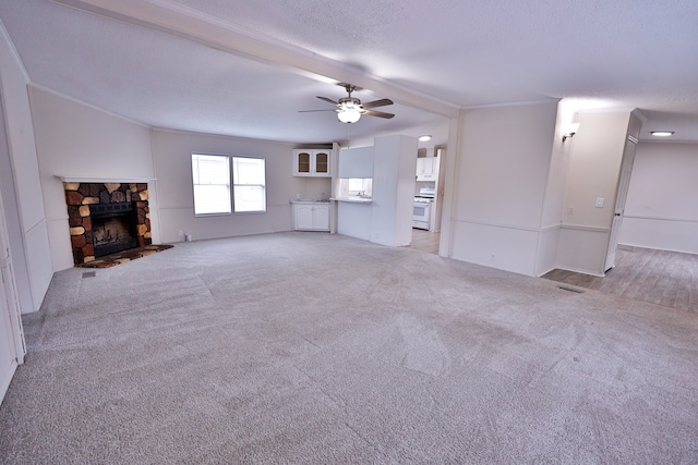 unfurnished living room featuring ceiling fan, light carpet, ornamental molding, and a stone fireplace