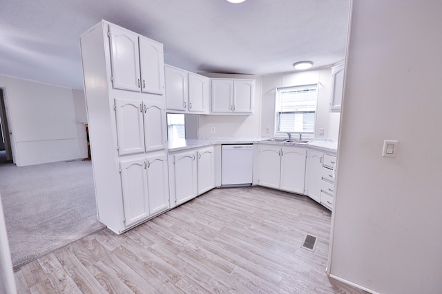 kitchen with dishwasher, a sink, white cabinetry, light countertops, and light wood-style flooring