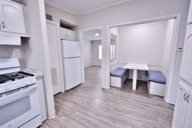 kitchen with white appliances, range hood, ornamental molding, light wood-style flooring, and white cabinetry
