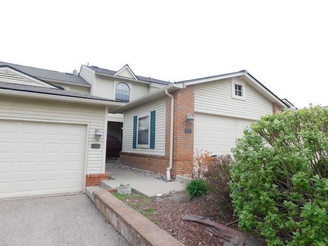 view of front of property featuring a garage, aphalt driveway, and brick siding