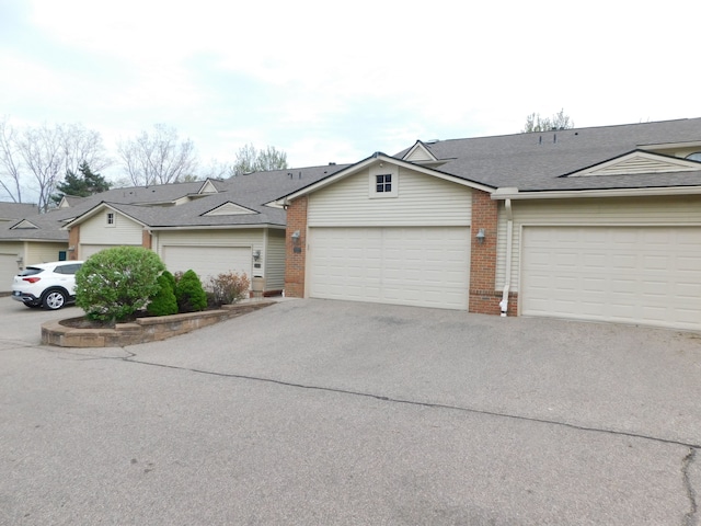 view of property with an attached garage, aphalt driveway, and brick siding