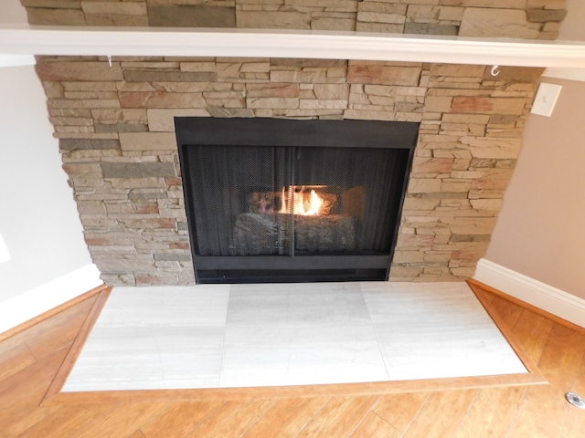 interior details featuring baseboards, wood finished floors, and a lit fireplace