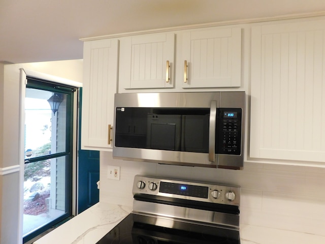 kitchen with appliances with stainless steel finishes, backsplash, white cabinets, and light stone countertops