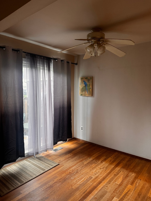 unfurnished room featuring a ceiling fan, plenty of natural light, and wood finished floors