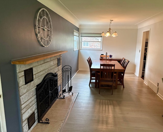 dining area with visible vents, a fireplace, baseboards, a chandelier, and hardwood / wood-style floors