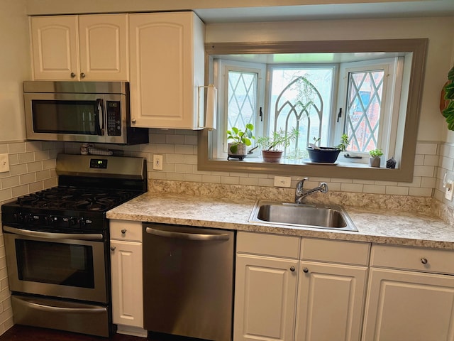 kitchen with white cabinets, appliances with stainless steel finishes, a sink, and light countertops