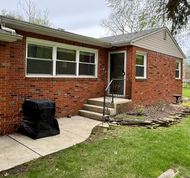 view of front of house with brick siding, a patio, and a front yard