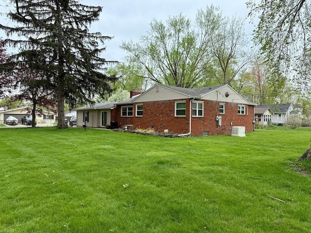 rear view of house with a yard, central AC, and brick siding