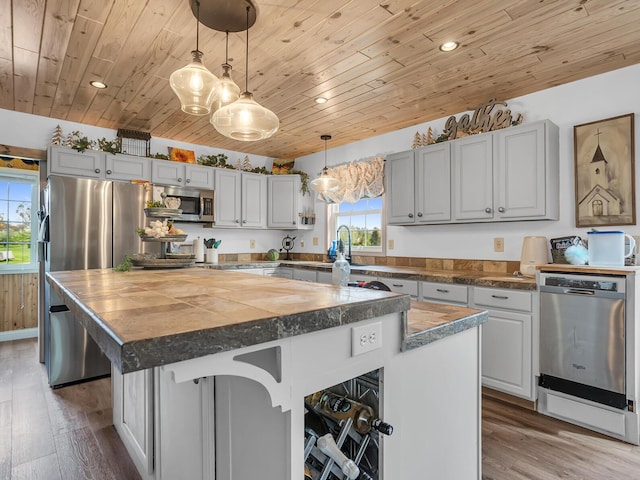 kitchen with stainless steel appliances, recessed lighting, wood finished floors, a kitchen island, and wood ceiling