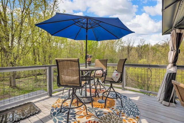 wooden deck featuring outdoor dining space and a wooded view