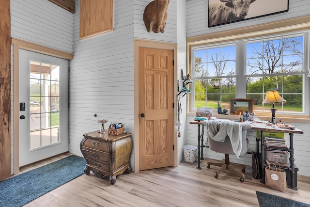 office space with wood walls, a towering ceiling, and wood finished floors