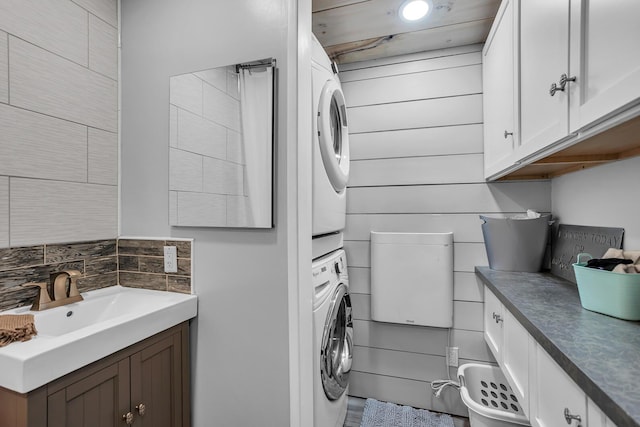 laundry room with stacked washer / drying machine, a sink, and laundry area