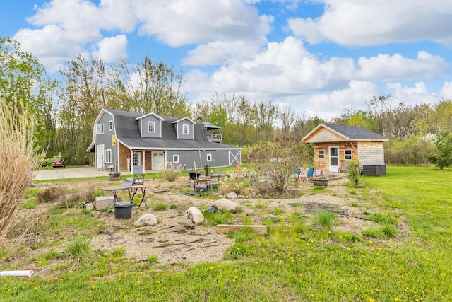 back of property featuring a lawn, an outdoor structure, and an outdoor fire pit