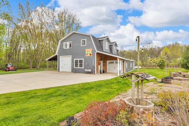view of side of home with a yard, driveway, a detached garage, and a gambrel roof