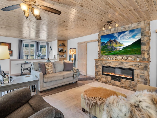 living area featuring a stone fireplace, a ceiling fan, baseboards, wood finished floors, and wood ceiling