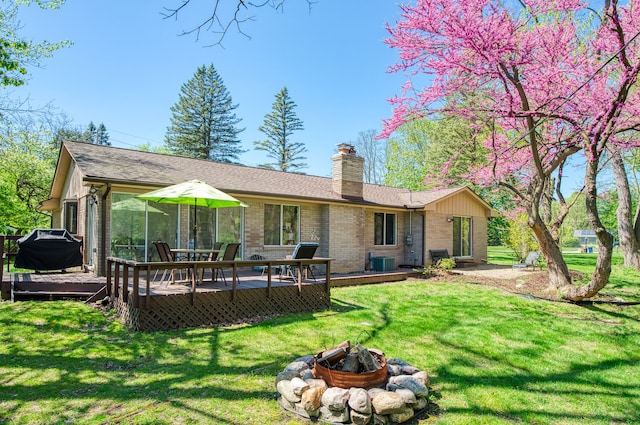rear view of house with an outdoor fire pit, a deck, a chimney, central AC, and brick siding