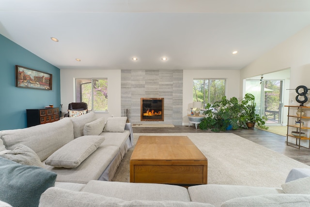 living area featuring plenty of natural light, lofted ceiling, wood finished floors, recessed lighting, and a tiled fireplace