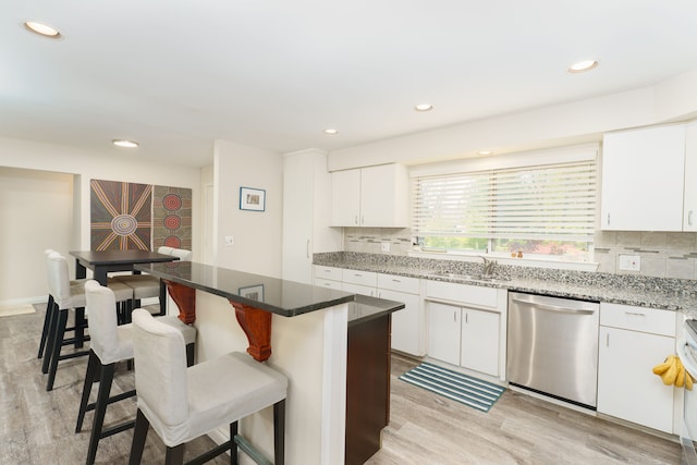 kitchen with dishwasher, a breakfast bar, backsplash, light wood finished floors, and white cabinetry