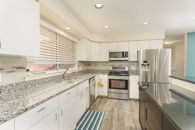 kitchen featuring stainless steel appliances, a sink, light stone counters, decorative backsplash, and recessed lighting
