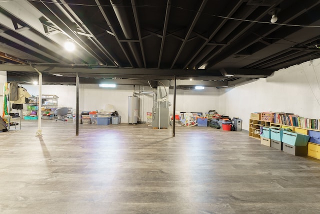 basement featuring water heater, heating unit, and wood finished floors