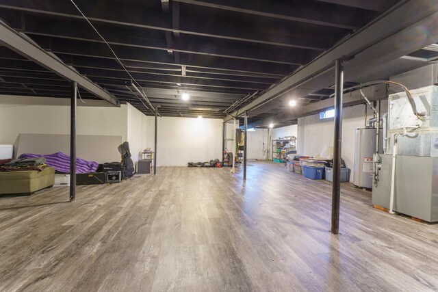 finished below grade area featuring gas water heater, wood finished floors, and heating unit
