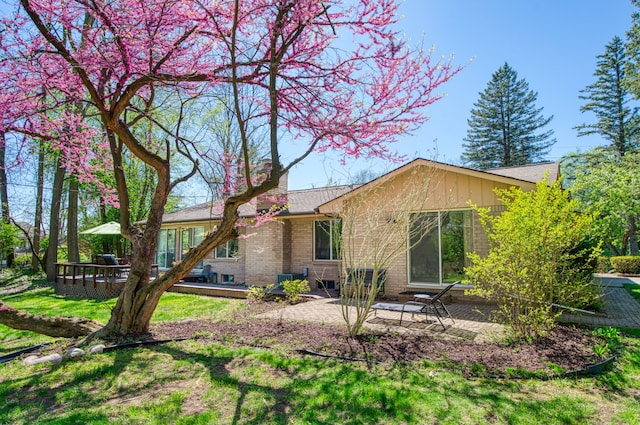 rear view of house with a patio, a chimney, brick siding, and a yard