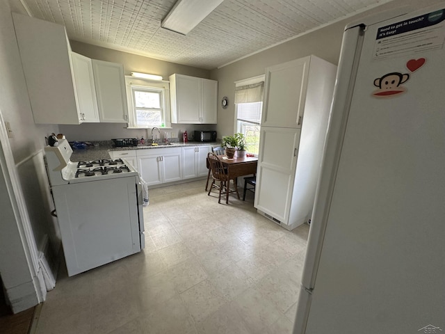 kitchen featuring light floors, a sink, white cabinetry, and white appliances
